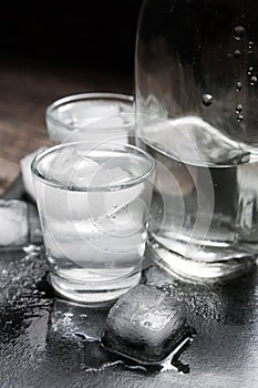 Close-up view of bottle vodka with glasses standing on ice black