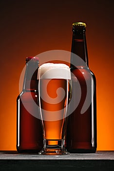 close up view of bottles and mug of beer with foam