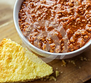 Close up view of a bowl of authentic chili, shown with a crumbly piece of buttermilk cornbread.