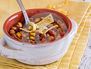 Close up view of a bowl of chili con carne garnished with corn chips.