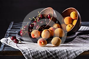 close up view of bowls with cherries and apricots on tray on wooden