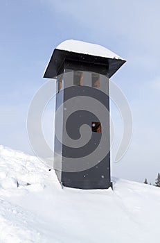 close-up view of brick stone pipe covered with metal sheets and black smoke box on snowy roof at winter