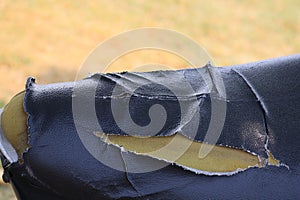 A close-up view of the broken leather seat of the motorcycle so that the sponge inside is visible.