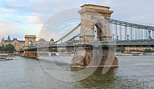 A close up view of the Budapest Chain bridge on the Danube river with Gresham Palace in the background