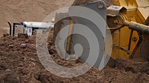 Close-up view of bulldozer moving large mass of sand with blade.