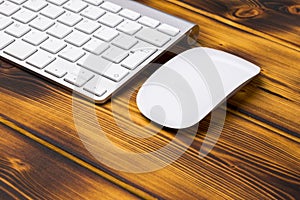 Close up view of a business workplace with wireless computer keyboard, keys and mouse on old dark burned wooden table background.