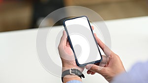 Close up view of businessman hand holding mobile phone with white screen.