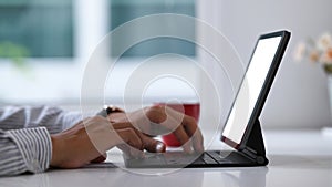 Close up view of businessman hands typing on keyboard of tablet computer at workspace.