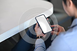 Businessman sitting at office desk and using mobile phone.