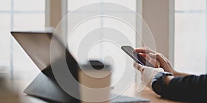 Close-up view of businesswoman touching smartphone in comfortable room