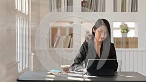 Close up view of  businesswomen typing on digital tablet sitting next to window in modern workplace