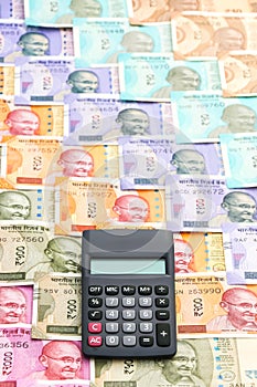 Calculator over brand new indian 10, 50, 100, 200, 500 and 2000 rupees banknotes. Colorful money pattern