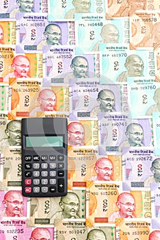 Calculator over brand new indian 10, 50, 100, 200, 500 and 2000 rupees banknotes. Colorful money pattern