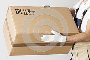 Close-up view of cardboard box in mover hands. Relocation services man in uniform with cardboard box.