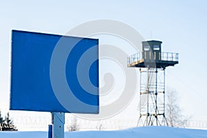 Close-up view of a caution banner, mock-up of a blue plate on an iron mesh fence against the surveillance tower. Closed area