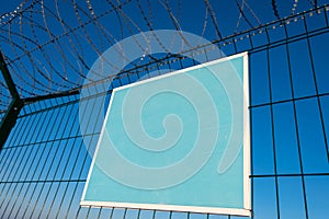 Close-up view of a caution banner, mock-up of a blue plate on an iron mesh fence with barbed wire. Closed area designation blank.