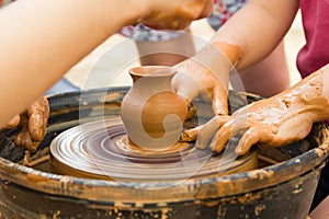 A close up view on ceramic production process on potter`s wheel with children. Clay crafts with kids concept