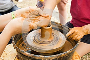 A close up view on ceramic production process on potter`s wheel with children. Clay crafts with kids concept