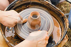 A close up view on ceramic production process on potter`s wheel with children. Clay crafts with kids concept