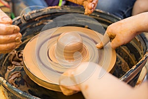 A close up view on ceramic production process on potter`s wheel with children. Clay crafts with kids concept