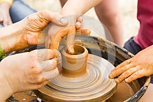 A close up view on ceramic production process on potter`s wheel with children. Clay crafts with kids concept
