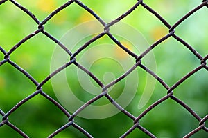 Close-up view of a chain link fence with mowed green field blurred into background.