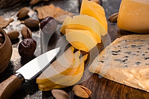 Close up view of cheese platter with knife, sliced pear, pistachios, olives and crackers