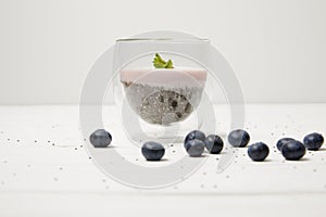 close up view of chia seed pudding with mint leaves and fresh blueberries on white tabletop