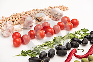 Close up view of chickpea, garlic, cherry tomatoes, parsley, chili pepper, olives on white background.