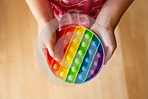 Close up view of child play with rainbow color push pop bubble sensory fidget toy. photo