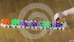 Close up view of child's hand spinning colourful plastic gears. Children and games concept