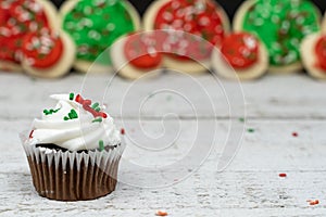 Close up view of chocolate Christmas holiday cupcake with sprinkles and vanilla buttercream frosting. Copyspace in background