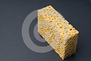 Close up view of cleaning sponge, mesh structure pattern on black surface. Yellow sponge close-up.