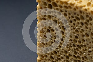 Close up view of cleaning sponge, mesh structure pattern on black surface. Yellow sponge close-up.