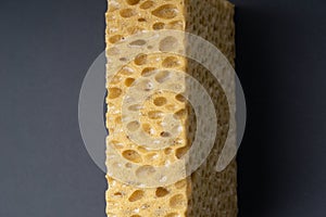 Close up view of cleaning sponge, mesh structure pattern on black surface. Yellow sponge close-up.