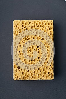Close up view of cleaning sponge, mesh structure pattern on black surface. Yellow sponge close-up.