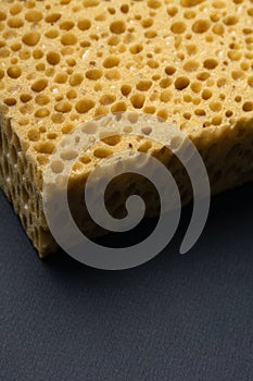 Close up view of cleaning sponge, mesh structure pattern on black surface. Yellow sponge close-up.