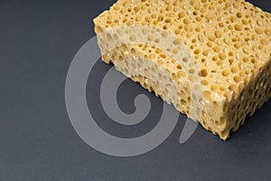 Close up view of cleaning sponge, mesh structure pattern on black surface. Yellow sponge close-up.