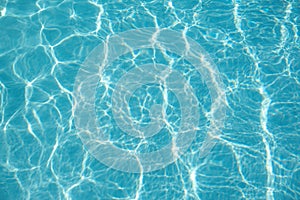 Bright turquoise blue swimming pool water surface with shimmering light reflections, Summer concept.