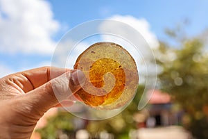 Close up view of clear Orange healing crystal held with hand against against sky