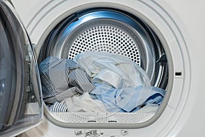 Close up view on clothes dryer with washed and dried shirts in and door open