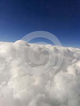 Close-up view of clouds from an airplane window against a blue sky