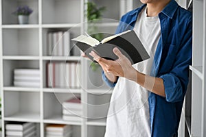 Close up view of college student reading book, lean against the book shelf