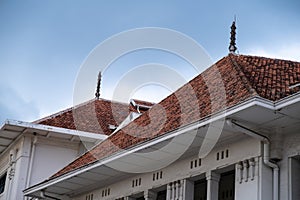 Close-up view of a colonial-style building\'s red tiled roof with decorative spires photo
