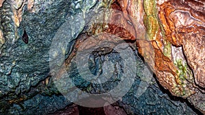 Close up view of colorful cave roof and dark tunnel in the background