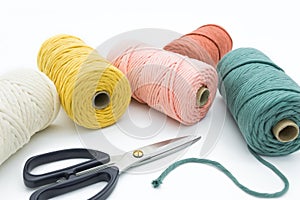 Close-up view of the colorful single strand cotton cords and scissor for macrame DIY handcraft