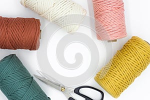 Close-up view of the colorful single strand cotton cords and scissor for macrame DIY handcraft isolated on white background