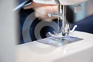 Close-up view of the components of the sewing machine, part of the needle with the thread and the presser foot.