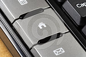 Close-up view of a computer keyboard key with a house icon on it, real estate business, home ownership, online housing markets