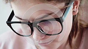 CLose up view of concetrated face of girl in glasses with black frame.